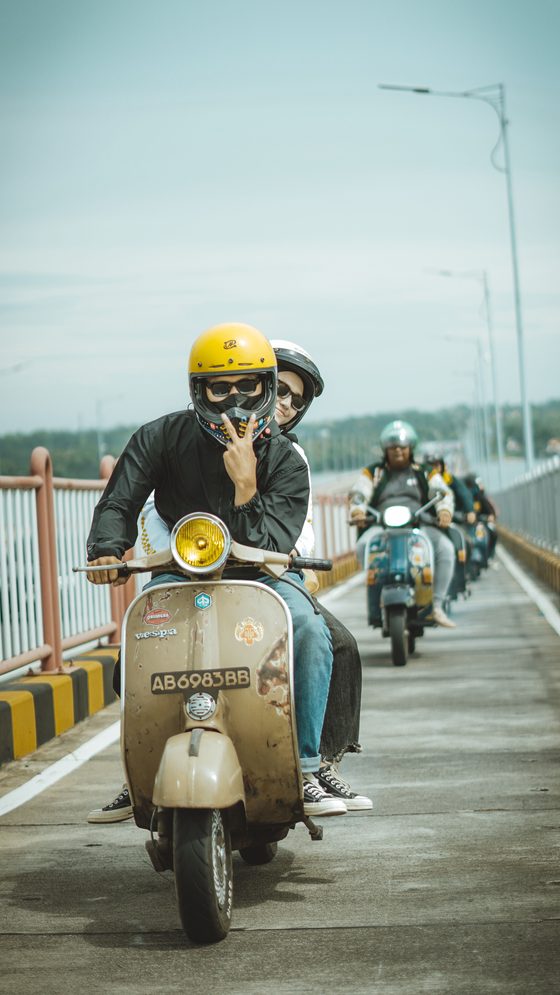 Riders on scooters crossing a bridge